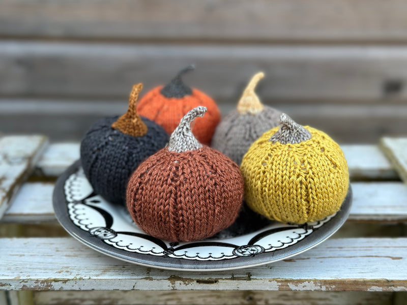 Four knitted pumpkins on a plate