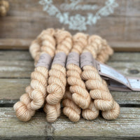 A pile of soft gold mini skeins with gold sparkle running through them