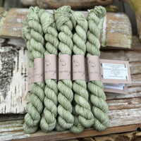 A pile of mini skeins of green yarn