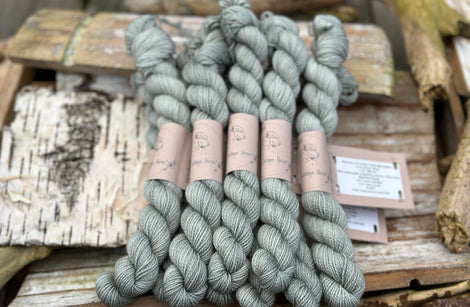 A pile of mini skeins of greenish grey yarn