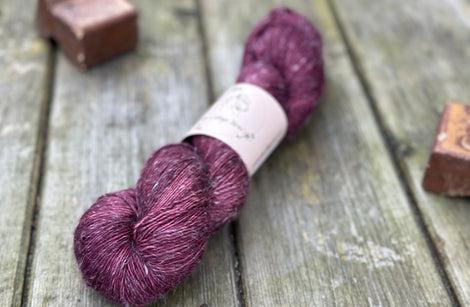 One skein of dark purple yarn with pale linen slubs running through it
