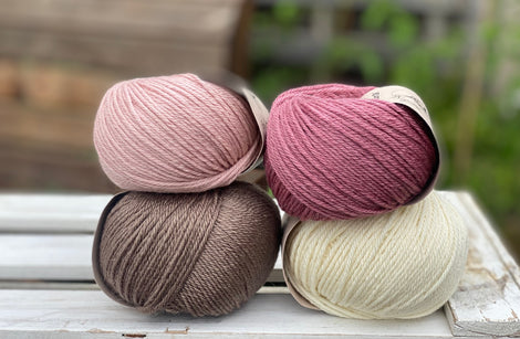 Four balls of yarn in two piles of two balls. On the left is a pink ball and a brown ball. On the right is a deep pink ball and a cream ball