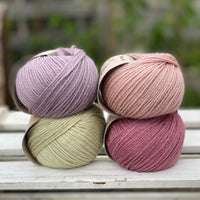Four balls of yarn in two rows of two. There is a pale purple ball, a light pink ball, a light green ball and a dark pink ball.