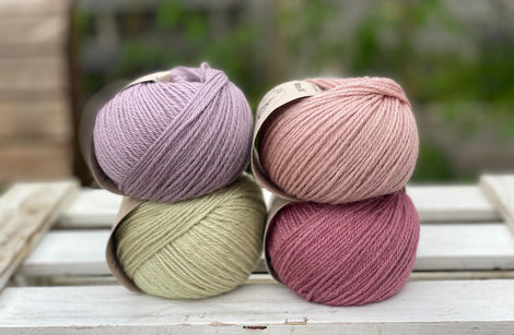 Four balls of yarn in two rows of two. There is a pale purple ball, a light pink ball, a light green ball and a dark pink ball.