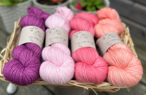 Four skeins of yarn in shades of pink and purple