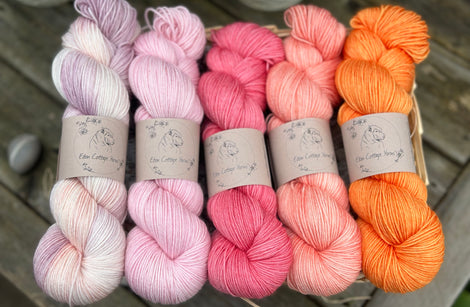 Five skeins of yarn in shades of pink, orange and cream