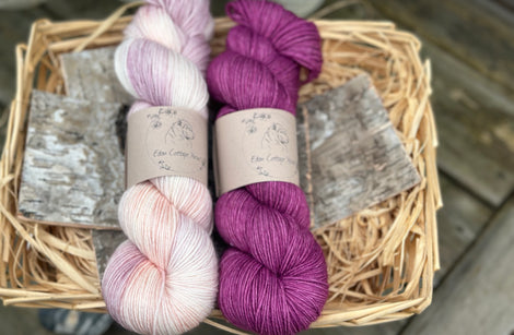 Two skeins of yarn - one variegated cream, pale purple and orange, one purple