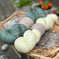 Two skeins of yarn - one blue-green skein and one pale yellow skein