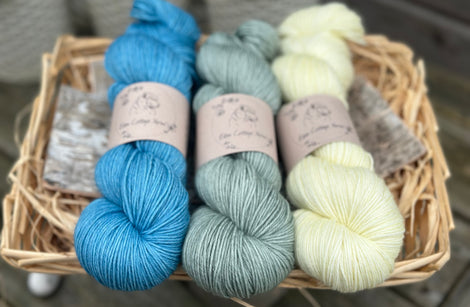 Three skeins of yarn. From left to right - a bright blue skein, a light blue-green skein and a pale yellow skein