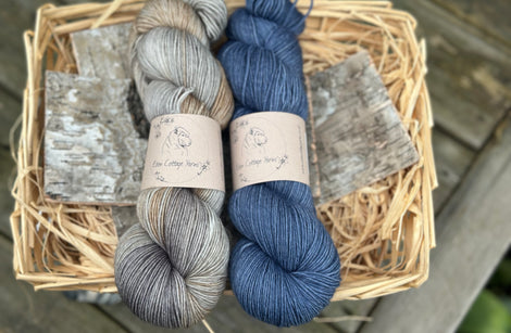 Two skeins of yarn - a variegated grey and brown skein and a dark blue skein