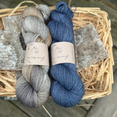 Two skeins of yarn - a variegated grey and brown skein and a dark blue skein