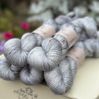 Five skeins of grey yarn with dark brown speckles