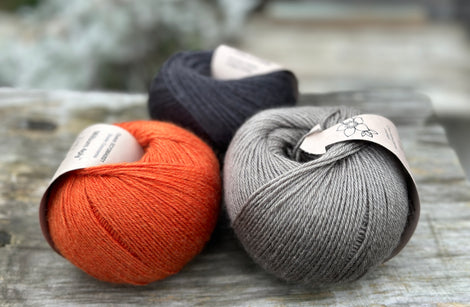 Three balls of yarn - one black, one orange and one grey