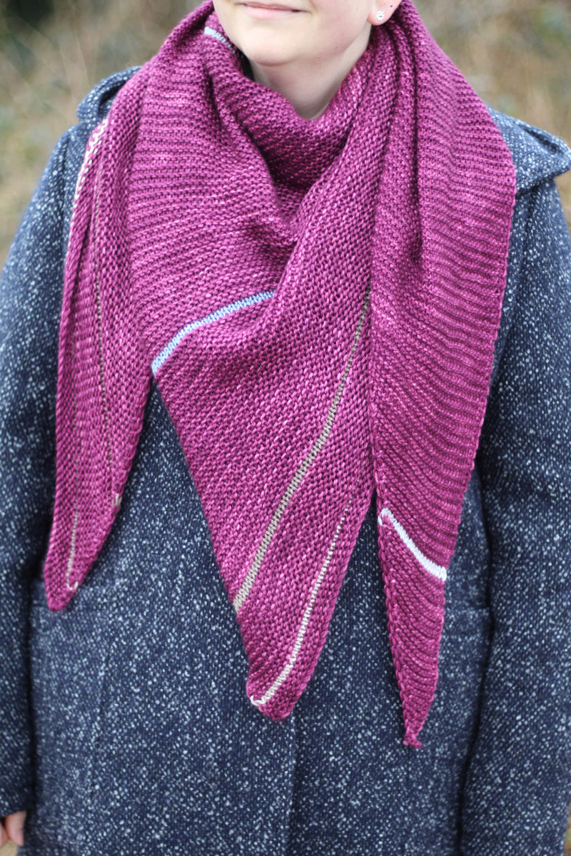 Victoria wearing a purpley pink triangular shawl wrapped around her neck. The shawl has stripes in muted contrast colours