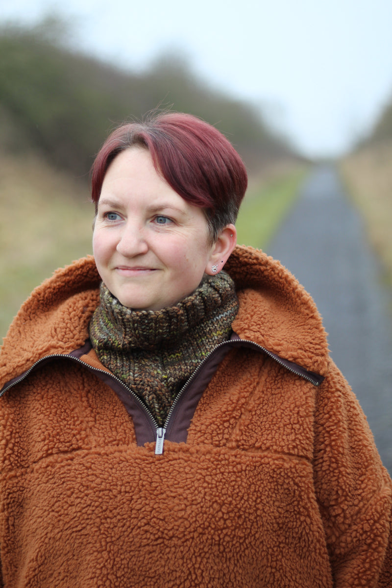 Victoria wearing a brown fleece and a variegated brown cowl with a single cable up the front.