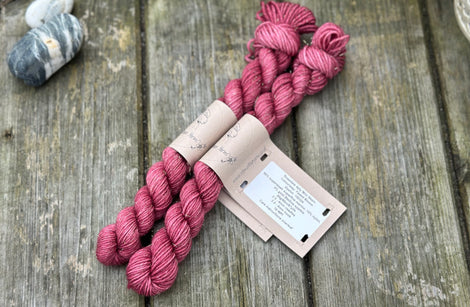 Two mini skeins of reddish purple yarn