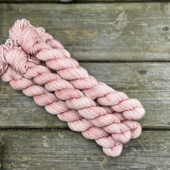 Five mini skeins of pink yarn with subtle gold sparkle running through it