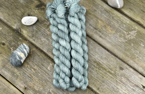 Five mini skeins of blue-green yarn with subtle gold sparkle running through it