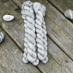 Five mini skeins of grey yarn with subtle gold sparkle running through it