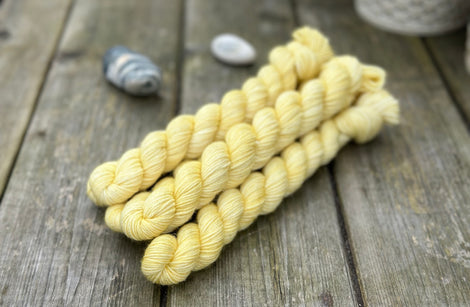 Yellow mini skeins of yarn with subtle gold sparkle running through it