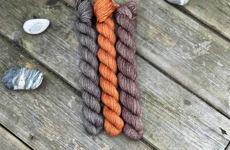 Three mini skeins. From left to right - a dark grey skein, a reddish brown skein and a brown skein