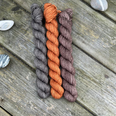 Three mini skeins. From left to right - a dark grey skein, a reddish brown skein and a brown skein