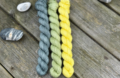 Three mini skeins. From left to right - a blue-green skein, a green skein and a yellow skein