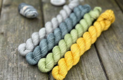 Four mini skeins. From left to right - a grey skein, a blue skein, a green skein and a yellow skein