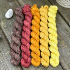 Five mini skeins of yarn in a fade from brown to yellow