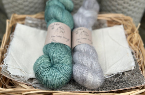Two skeins of yarn - one green and one fluffy grey