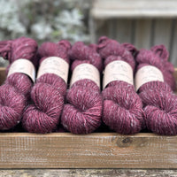 Skeins of dark purple yarn with white slubs running through them