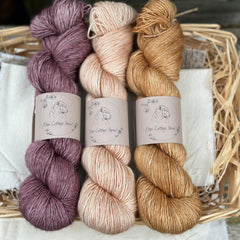 Three skeins of yarn in shades of purple and brown