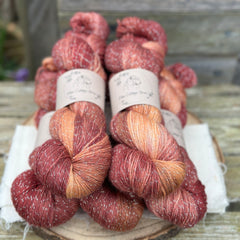 Five skeins of variegated red and gold yarn with silver sparkle running through it
