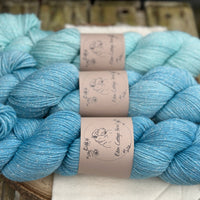 Three skeins of yarn in shades of blue with silver sparkle running through it