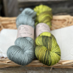 Two skeins of yarn - one grey and one variegated green and brown