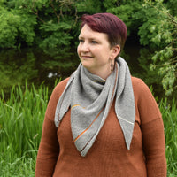 Victoria wearing a rusty brown jumper and a triangular grey shawl. The shawl is grey with thin stripes of contrasting colours