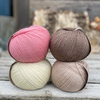 Four balls of yarn. Colours are natural cream, beige, pink and brown