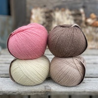Four balls of yarn. Colours are natural cream, beige, pink and brown