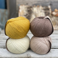 Four balls of yarn. Colours are natural cream, beige, yellow and brown