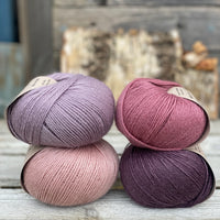 Four balls of yarn. Colours are pale pink, purple, pale purple and deep pink