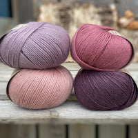 Four balls of yarn. Colours are pale pink, purple, pale purple and deep pink