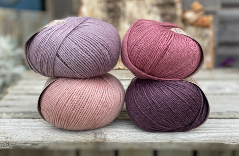 Four balls of yarn. Colours are pale pink, purple, pale purple and deep pink