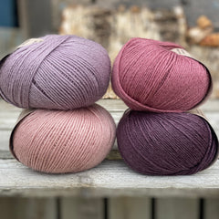 Four balls of yarn. Colours are pale pink, purple, pale purple and deep pink