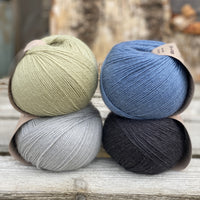 Four balls of yarn. Colours are pale blue, blue, pale green and black