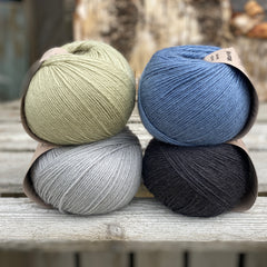 Four balls of yarn. Colours are pale blue, blue, pale green and black