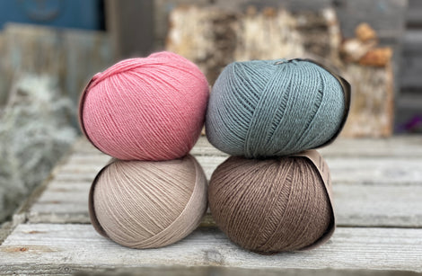 Four balls of yarn. Colours are beige, pink, teal and brown