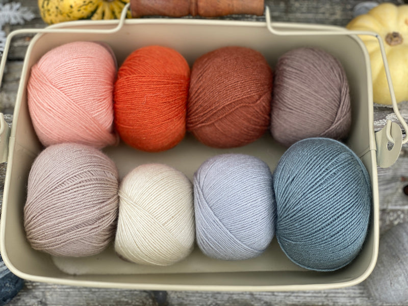 Eight balls of Milburn 4ply in shades of orange, brown and blue