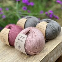 Four balls of yarn in grey and pinks