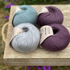 Four balls of yarn in purple and blues