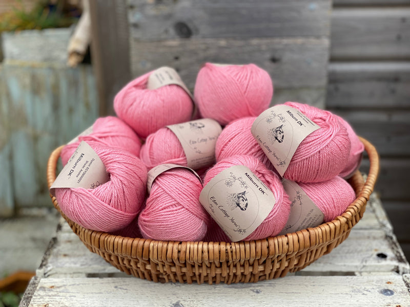 A basket filled with balls of pink yarn